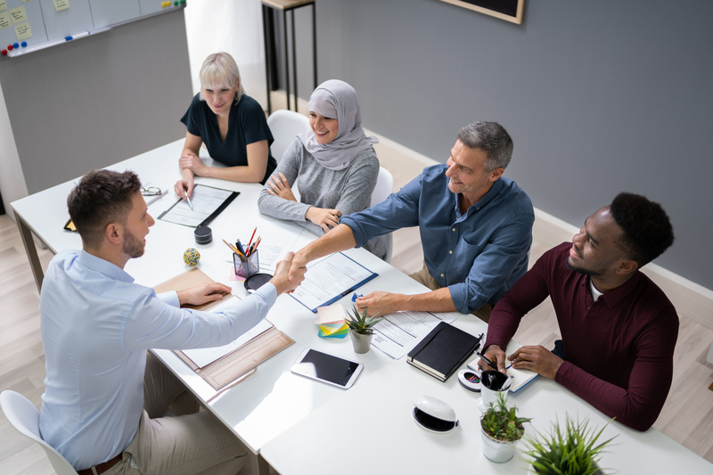 Two men and two women sit across the table from a man interviewing for a job.