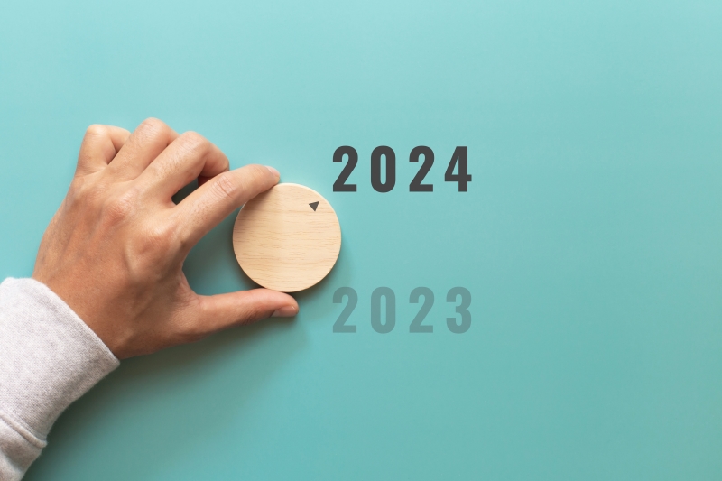 Hand turning the year from 2023 to 2024